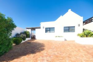 uma casa branca com uma entrada de tijolos em Owlet Cottage In Arniston em Arniston