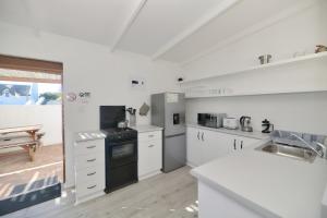 uma cozinha com balcões brancos e um forno com placa de fogão em Owlet Cottage In Arniston em Arniston