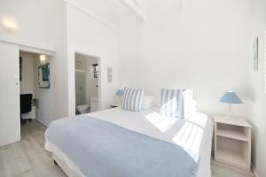 um quarto branco com uma grande cama branca com almofadas listradas em Owlet Cottage In Arniston em Arniston