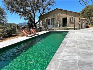 una piscina con 2 sillas y una casa en VILLA A MUREDDA, piscine chauffée et vue mer, en Olmeto