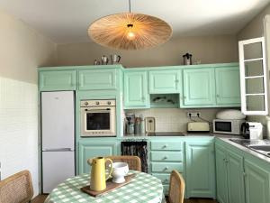 a kitchen with mint green cabinets and a table at VILLA A MUREDDA, piscine chauffée et vue mer in Olmeto