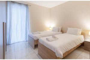 - une chambre avec 2 lits et une fenêtre dans l'établissement Modern SeaFront 3bedrooms Apartment, à San Pawl il-Baħar