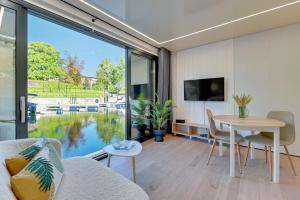 a living room with a table and a large window at Domy Na Wodzie - La Mare Motlava Houseboats with Sauna by Downtown Apartments in Gdańsk