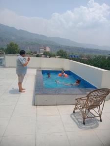 un hombre de pie junto a una piscina en el techo en Amigo Rooms, en Rishīkesh