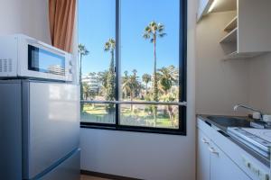 a kitchen with a refrigerator and a window with palm trees at Miyazaki Mango Hotel - Vacation STAY 58309v in Miyazaki