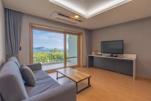 a living room with a couch and a large window at Seaore Resort in Seogwipo