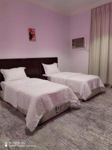 two beds in a room with white walls at فندق وشقق ليالي الاحلام للشقق المخدومه in Baljurashi