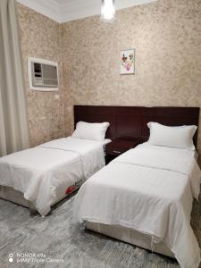 two beds in a hotel room with white sheets at فندق وشقق ليالي الاحلام للشقق المخدومه in Baljurashi