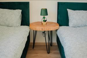 a table with a lamp on it next to two beds at Green House Happy in Macharce +22 photos