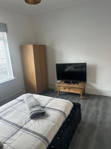 a bedroom with a bed and a flat screen tv at Sheriff suites in Hartlepool