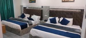 1 dormitorio con 2 camas y almohadas azules y blancas en HOTEL NEW BADRINATH, en Badrīnāth