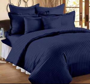 ein Bett mit einer blau gestreiften Bettdecke und Kissen in der Unterkunft HOTEL NEW BADRINATH in Badrīnāth