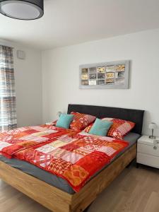 Schlafzimmer mit einem Bett mit einer roten und orangefarbenen Decke in der Unterkunft Ferienwohnung MiKa in Friedrichshafen