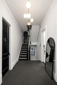 einen Flur mit einer Treppe mit einer schwarzen Tür und einem Spiegel in der Unterkunft VENUS Harbourside - FEMALE ONLY HOSTEL in Sydney