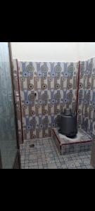 een badkamer met een betegelde muur en een toilet bij WISMA TIGA PUTRA BELAWA 2 in Topoyo
