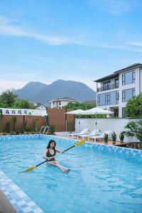 a woman paddling a kayak in a swimming pool at 莫干山雅泉山居 in Deqing