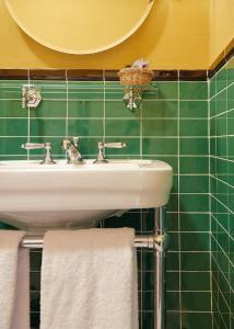佛羅倫斯的住宿－赫米緹吉酒店，一间带水槽和绿色瓷砖墙壁的浴室