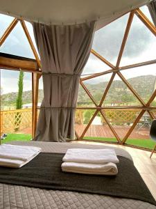 - une chambre avec 2 serviettes blanches sur un lit et une grande fenêtre dans l'établissement Amazing Cyprus Glamping Domes - Glamping Cyprus, à Paphos