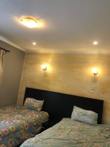 a bedroom with two beds and two lights on the wall at Nersheys 2 bedroom Apartment near Junction Mall in Nairobi