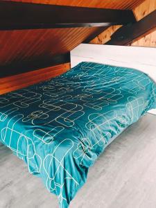 a bed with a blue and white comforter on it at Chalet idéal 4-8 pers avec garage 20 mn Gérardmer in Vienville