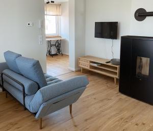 a living room with a blue chair and a tv at NEU Ferienwohnung am Kloster, ländliche Idylle mit der ganzen Familie in Leinefelde