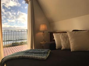 Alonnah的住宿－The Roundhouse-Waterfront Stay，一间卧室设有一张床和一个美景阳台