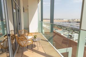 Bloomfields -1br Oasis 2 في أبوظبي: بلكونه فيها كراسي وطاولة وإطلالة على المطار