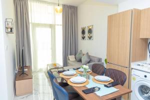 Bloomfields -1br Oasis 2 في أبوظبي: مطبخ وغرفة معيشة مع طاولة وكراسي