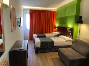 Habitación de hotel con 2 camas y sofá en Apartamentos Recoletos, en Madrid