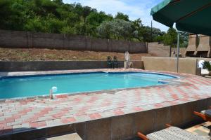 a swimming pool with a brick patio and an umbrella at Kamogelo Guest House in Pilanesberg
