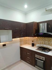 a kitchen with wooden cabinets and a stove top oven at Balqees Cottage in Lahore