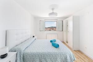 ein weißes Schlafzimmer mit einem Bett mit einer blauen Decke in der Unterkunft Casa Parraga in Cehegín