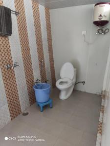 a bathroom with a toilet and a blue bucket at Dhanolti Resort in Dhanaulti