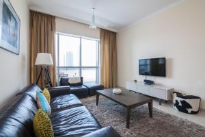 a living room with a leather couch and a tv at Bay Central Tower in Dubai