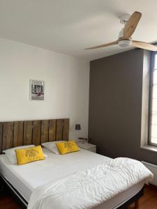 - une chambre avec un lit doté d'oreillers jaunes et d'un ventilateur de plafond dans l'établissement Jolie location contemporaine dans Saint Martin de Ré, à Saint-Martin-de-Ré