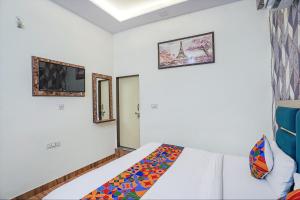 een slaapkamer met een bed en twee foto's aan de muur bij FabHotel Jimmy Palace in Tājganj