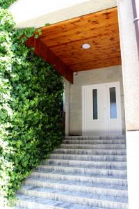 uma escada que conduz a uma porta branca com uma cerca verde em Apartmanový dom Stummerova em Topoľčany
