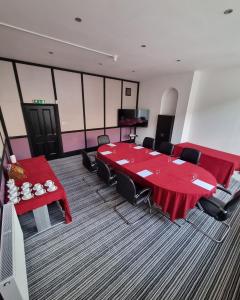 a conference room with a red table and chairs at George Hotel by Greene King Inns in Huntingdon