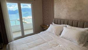 a bedroom with a white bed with a large window at Hotel Demoli in Pogradec