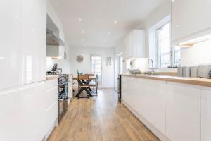 cocina con armarios blancos y suelo de madera en Eton House coastal villa with great outside space en Sheringham