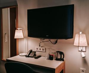 TV a schermo piatto appesa a un muro con telefono di Hotel Noreg ad Ålesund
