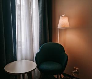 um quarto com uma cadeira verde, um candeeiro e uma mesa em Hotel Noreg em Ålesund