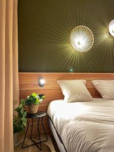 ベルサイユにあるHôtel le Bout du Parcのベッドルーム1室(ベッド1台、植物のあるテーブル付)