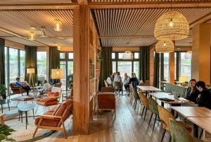 un restaurante con mesas y sillas y personas sentadas en mesas en Hôtel le Bout du Parc en Versalles