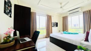 1 dormitorio con 1 cama y escritorio con ordenador portátil en BluO Lake Facing 1BHK NewTown, Terrace Garden, Gym, en Calcuta