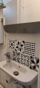 un bagno con lavandino e fiori sul muro di Cosy Appartement Paris Ouest a Suresnes