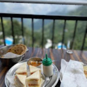 a table with a plate of sandwiches and a spoon at Dhanolti Resort in Dhanaulti