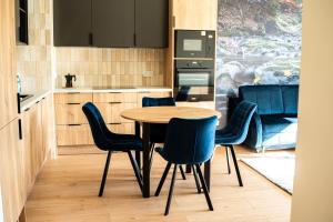 a kitchen with a wooden table and blue chairs at Apartamenty Lesko 36 in Lesko