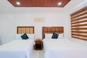 2 letti in una camera con pareti bianche di Q Beach Resort a Cabangan