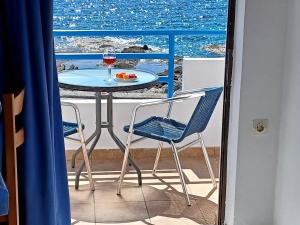 d'une table, de chaises et d'un verre de vin sur le balcon. dans l'établissement Haris Studios, à Paleóchora